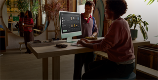 Two people in a well-lit room, viewing products on the iMac nano-texture glass display