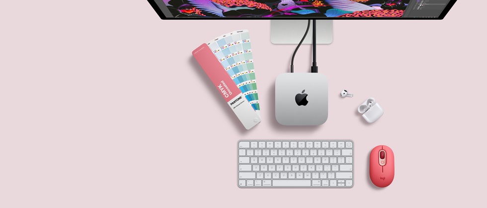 Mac mini, top, silver aluminum, rounded corners, glossy black Apple logo centered, connected by cord, Studio Display partially visible on top, AirPod 4, open, Pantone color swatches, and red Logitech keyboard and mouse