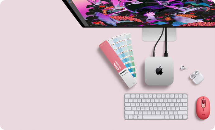 Mac mini, top, silver aluminum, rounded corners, glossy black Apple logo centered, connected by cord, Studio Display partially visible on top, AirPod 4, open, Pantone color swatches, and red Logitech keyboard and mouse